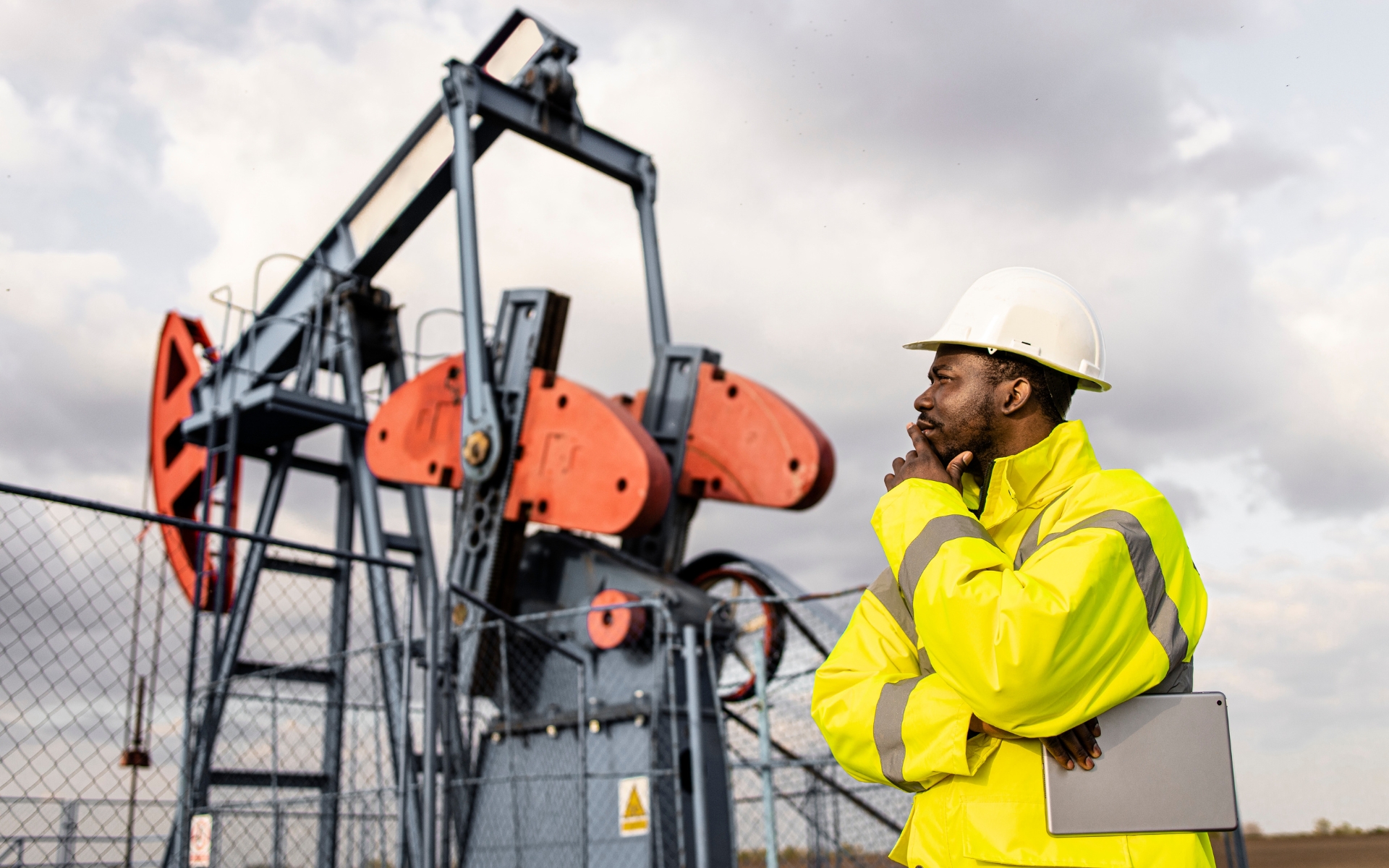 Engineer examining oil pump in field.