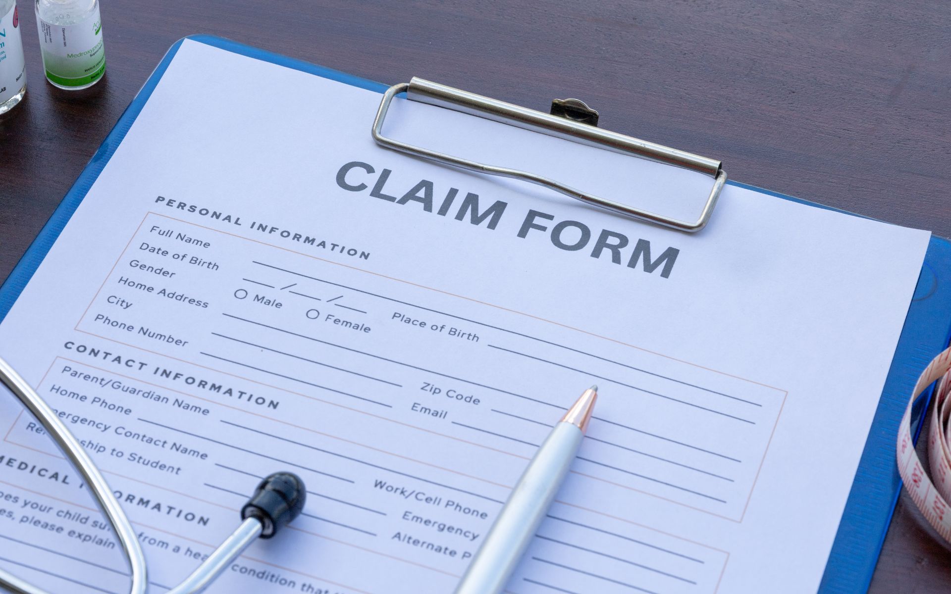 Claim form with pen and stethoscope on table.